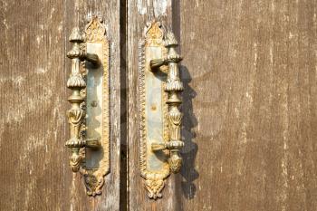 lentate abstract   rusty brass brown knocker in a  door curch  closed wood italy  lombardy 