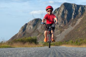 Happy smiling boy riding a bicycle. Andoya, Norway. Summer shot