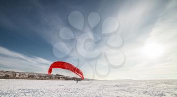 Kite surfer being pulled by his kite across the snow