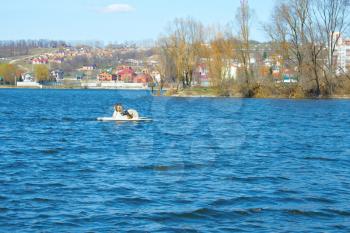 Two women walking on water bikes at the city reservoir an early spring in lovely sunny weather. Khmelnytsky, Ukraine