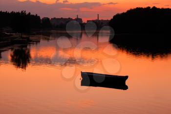 View anchored boat in the reservoir after sunset in quiet summer weather. Khmelnitsky, 