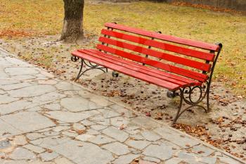 The old red wooden bench in the autumn park
