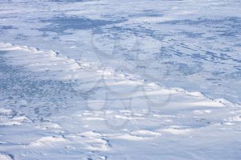 Snow hummocks on the surface of frozen reservoir