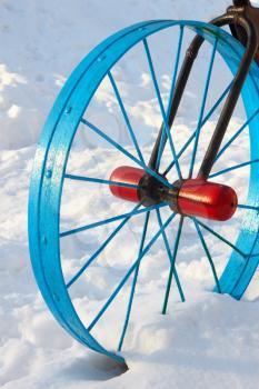 Metallic painted detail in the form of a bicycle wheel in the snowdrift in winter season outside