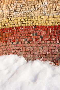 Fragment of an old colortul mosaics partially covered with snow in fine winter day