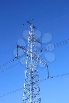 Electrical high-voltage metal pillar against the background of blue cloudless sky