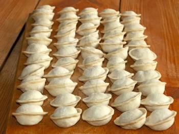 Frozen meat dumplings on the kitchen board. Dumplings or ravioli is a traditional East Slavic kitchen dish or other name as pelmeni