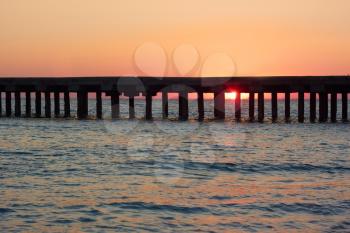 Old sea pier during the beautiful sunset over the sea coast