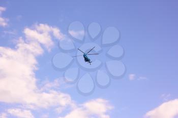 Helicopter flying against the background a blue sky with white clouds
