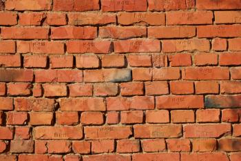 Red brick wall with clay mortar in bright sunlight