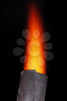 Red torch flame over the old metal chimney at night