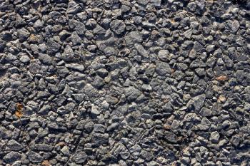 Fragment of the road surface with small stones and bitumen. Close-up 