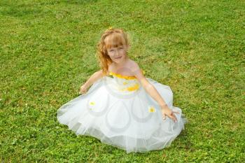 Little girl in a yellow festive dress on a green lawn