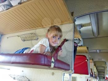 Little girl lying on a shelf of carriages while traveling by train