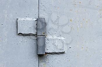 Metal hinge welded to the two steel plates, painted in light gray color, close-up