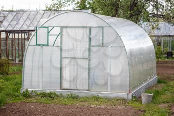 A small greenhouse with air vents in the garden