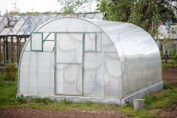 A small greenhouse with air vents in the garden