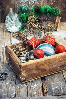 Wooden box full of Christmas toys and cones on wooden background.Selective focus