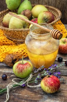 Autumn harvest of apples in the background of the glass jar with fragrant honey.Photo tinted