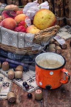 composition of the enamel cup with water on the background  fruit basket and Lotto games for picnic