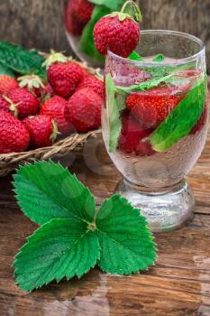 glass with drink of strawberries and mint on the background of the basket full berries.Selective focus.Photo tinted