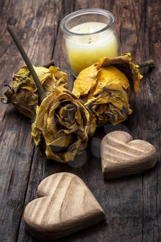 hand-carved symbolic wooden heart on background of yellow roses