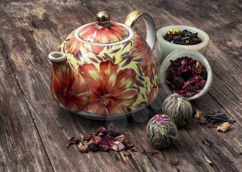 teapot and scattered tea leaves on vintage wooden background