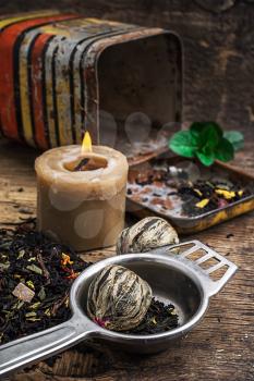 burning candle on the background of scattered tea with lime and mint in rustic style.Selective focus