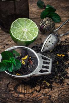 tea brew with lime and mint on wooden background in rustic style.