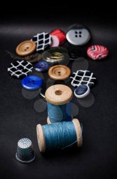 thread and buttons for sewing master on black background.Selective focus