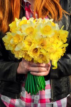 silhouette of girl with red hair with bouquet of daffodils hands.Selective focus