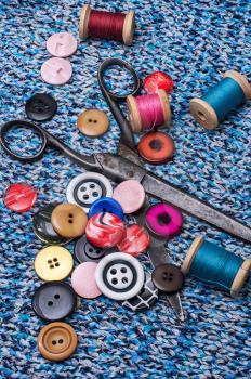 old scissors and thread and buttons on textured background fabric