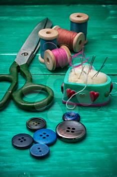 scattering of buttons,thread and needle on turquoise background.Selective focus