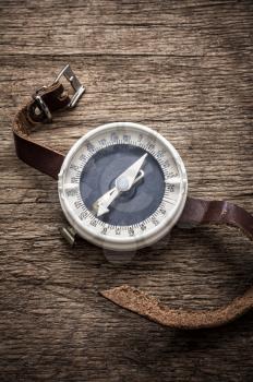 obsolete compass with leather strap on wooden table top in retro style