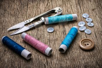 Scissors ,thread and buttons on unhewn darianna background in vintage style