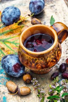 Mug with herbal medicinal tea on an autumn fruit,chestnuts and acorns on metal background.