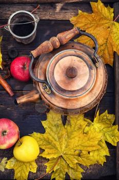 Copper teapot in the background osennih maple leaves and apples