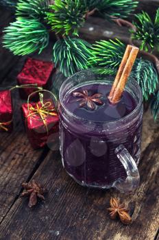 A glass of wine with the cinnamon stick and star anise amid the branches of the spruce.