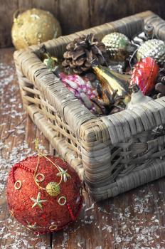 Braided straw basket full of cones and Christmas ornaments.