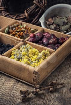 Dried medicinal herbs in wooden box on background of licorice