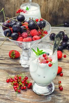 Glass goblet with milkshake with strawberries and currants