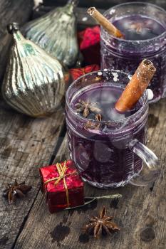 glass of wine with the cinnamon stick and star anise amid the branches of the spruce.