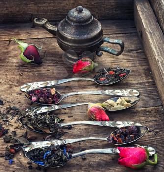 Varieties of tea brewed in an iron spoon on the background of symbolic teapot