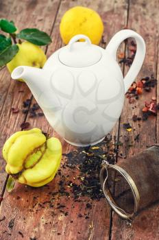 White glass teapot and quince tea on wooden background
