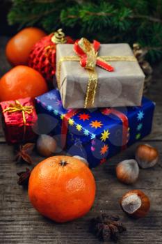 Two small boxes with gifts on the background of tangerine,spruce branch,hazelnuts 