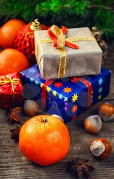 Two small boxes with gifts on the background of tangerine,spruce branch,hazelnuts 