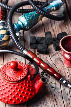Details of Smoking hookah and red metal kettle spilled tea leaf