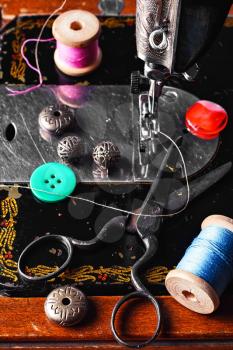 Scissors,button and thread on the background of the sewing machine the old model