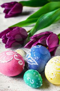 Decorated with painted Easter eggs and bouquet of tulips on  light background