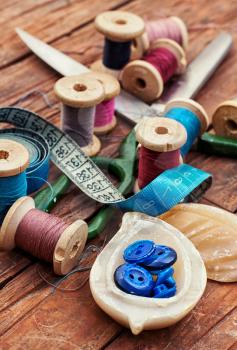  button and spools of thread for needlework on bright background